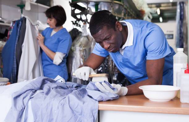 Experienced African-American man working in modern dry cleaner